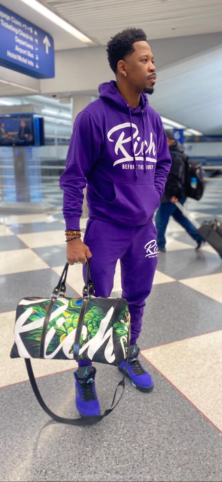 Brian E. Sibley at the airport in head-to-toe purple Rich Before The Money apparel