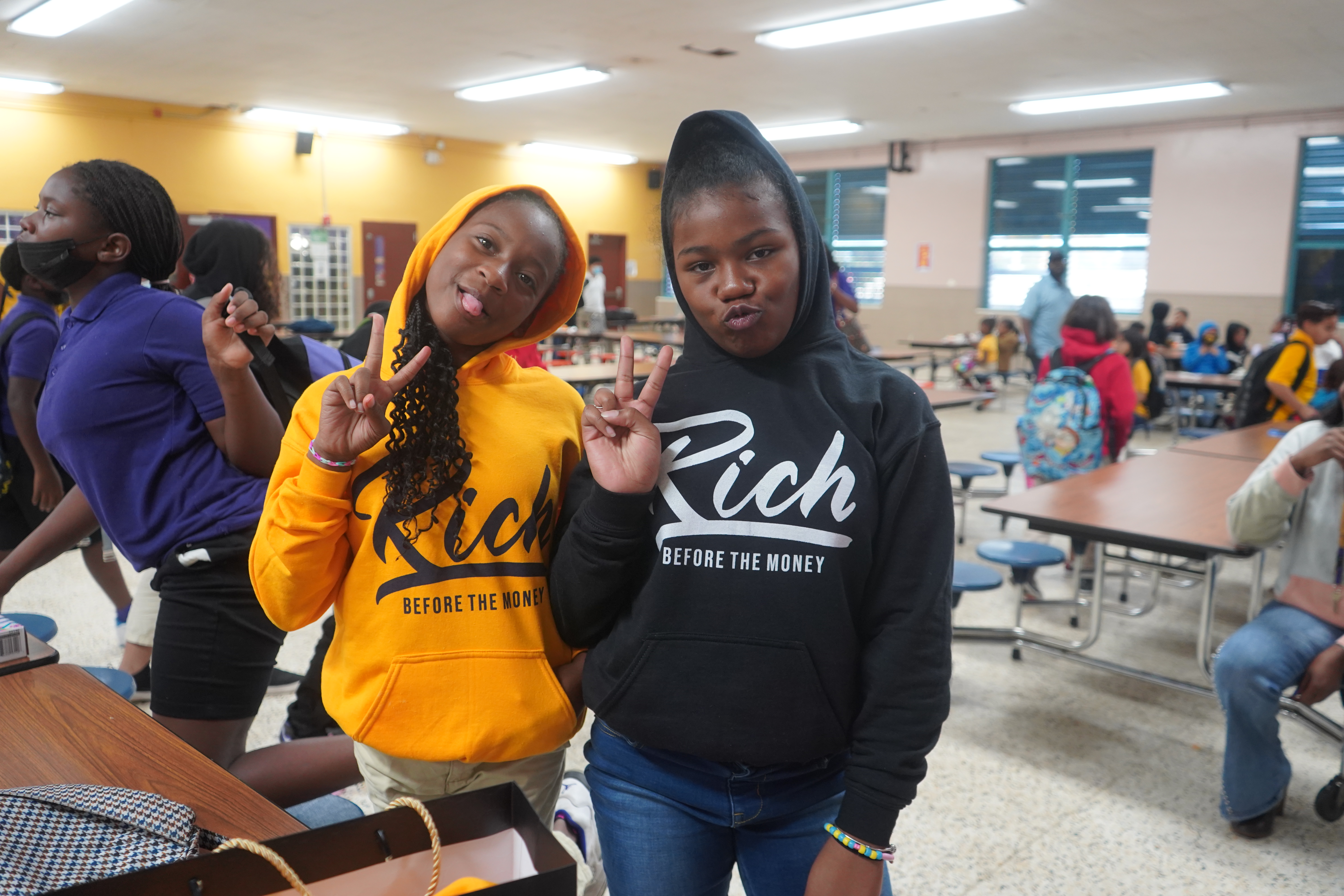 Two students wearing Rich Before The Money hoodies