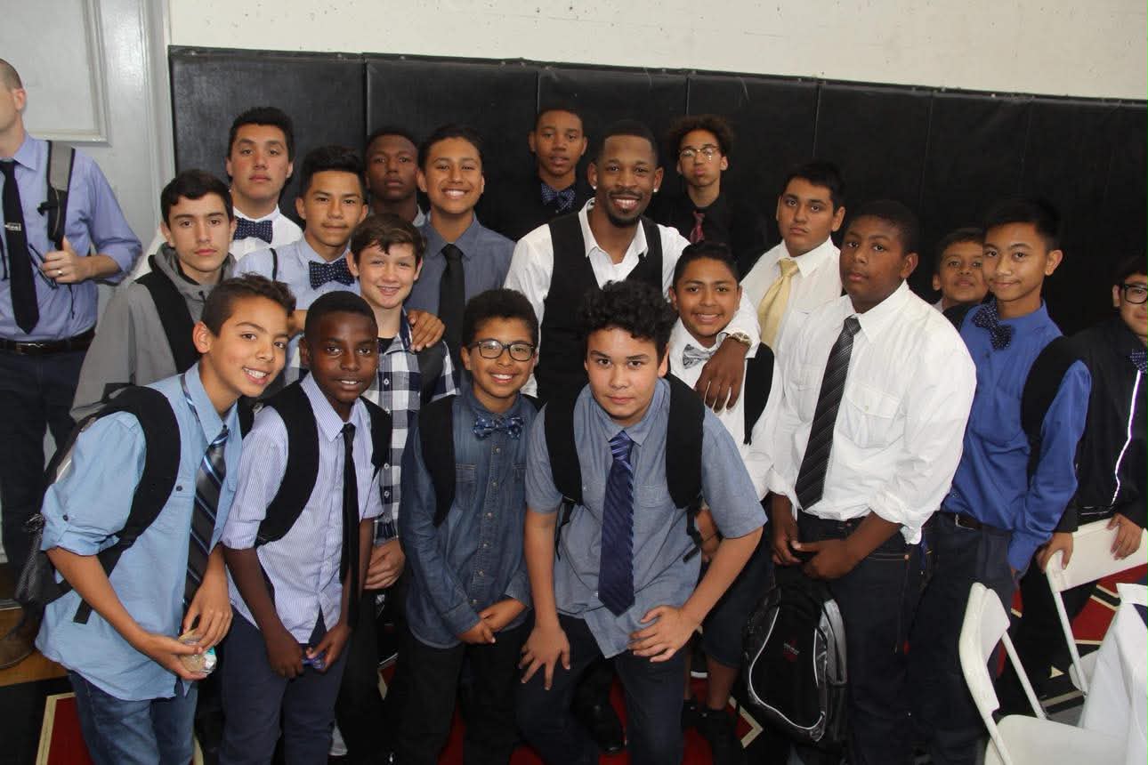 Brian E. Sibley surrounded by a large group of young men in shirts and ties at a school event